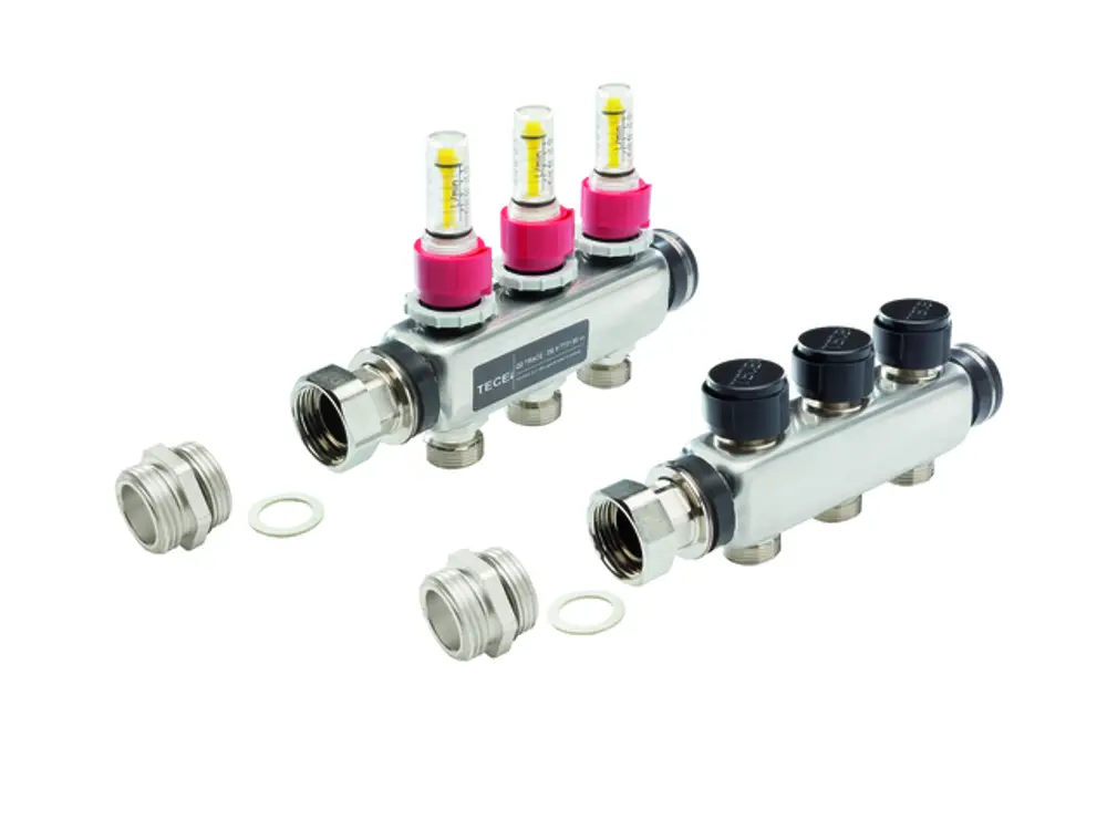 TECE-Ventilblock mit zwei Durchflussmessern in pink, verbunden mit drei Anschlussstellen, sowie zwei Übergangsnippeln in der Nähe, dargestellt auf hellem Hintergrund.